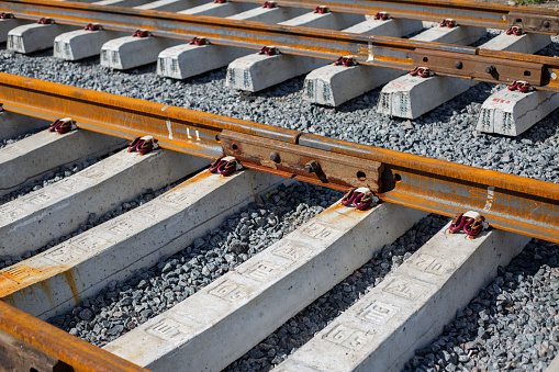 Rusty intermediate rail fasteners on concrete sleepers for train and tram, laying railroad tracks