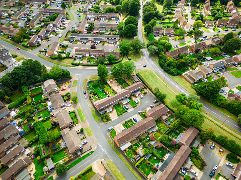 Aerial view, shot by drone, depicting houses and gardens and residential streets of a town (Crawley) in southeast England.