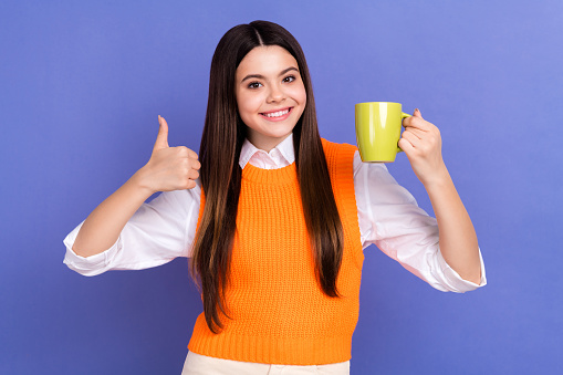 Portrait of satisfied young girl wear orange trendy vest thumb up rate new cafeteria morning cappuccino isolated on violet color background.