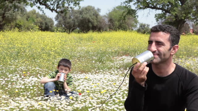 Father and son talking on can phone