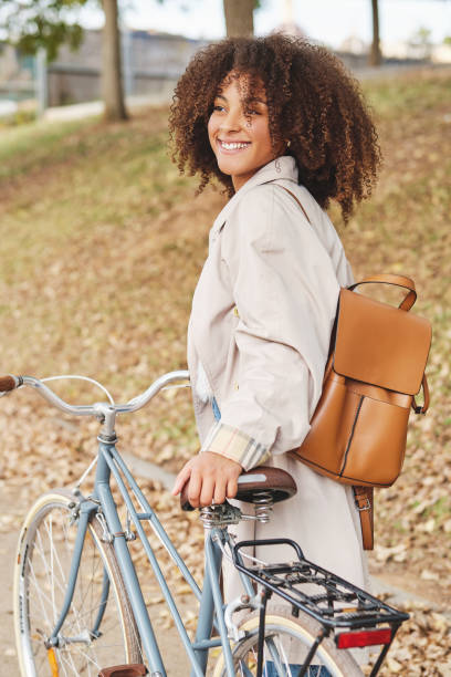 istock Smiling black woman with bicycle in autumn park 1605119521