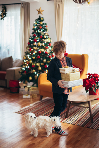 Boy holding stack of Christmas presents that he just received for Christmas
