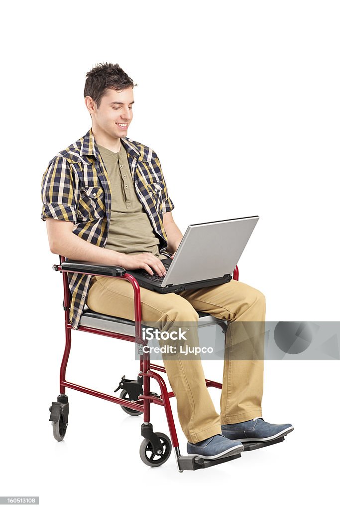 Joven hombre discapacitado en silla de ruedas, trabajando en la computadora portátil - Foto de stock de Adolescencia libre de derechos