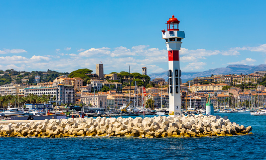 Cannes, France - July 31, 2022: Cannes seafront panorama with lighthouse on breakwater and yacht port at French Riviera of Mediterranean Sea