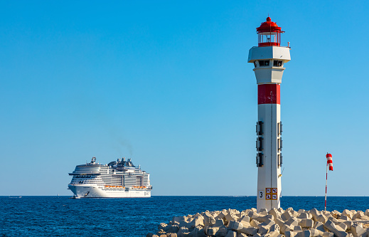 Cannes, France - July 31, 2022: Cannes seafront panorama with lighthouse on breakwater and MSC Meraviglia cruiser ship offshore French Riviera on Mediterranean Sea