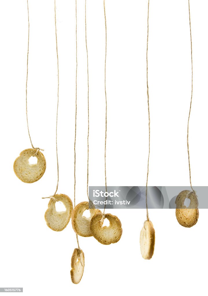 Hanging by a string. Hanging pieces of baked bread on white background. Baked Stock Photo