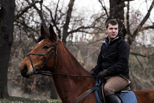 Young man riding a horse in nature.
