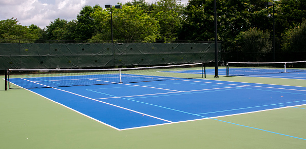 Wide view of two blue and green tennis courts that are also lined for pickleball games.