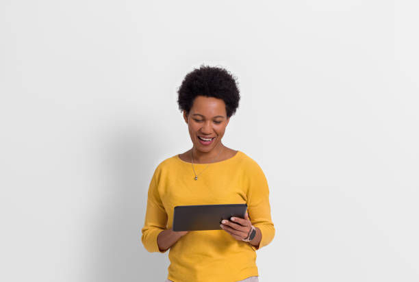 istock Smiling young female freelancer with afro hairstyle working over digital tablet on white background 1605162846