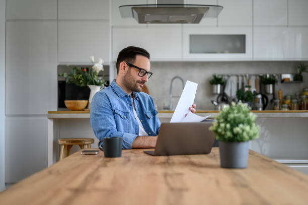 istock Young entrepreneur with laptop on desk analyzing financial report while working from home office 1605164445