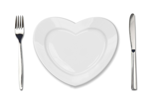 plate in shape of heart, table knife and fork isolated on white