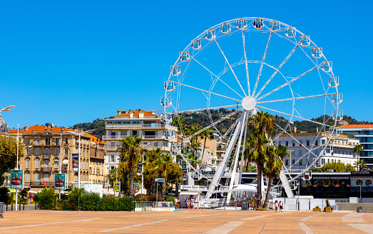 Cannes, France - July 31, 2022: Grande Roue Ferris Wheel at Promenade de la Pantiero square aside Palace of Festivals and Congresses and yacht marina in Cannes on French Riviera