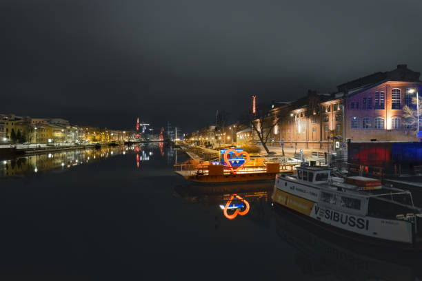 Turku, Finland - December 5, 2022: The city's beautiful riverside comes alive on a crisp winter evening, as the lights of the city reflect upon the tranquil surface of the Aura river.