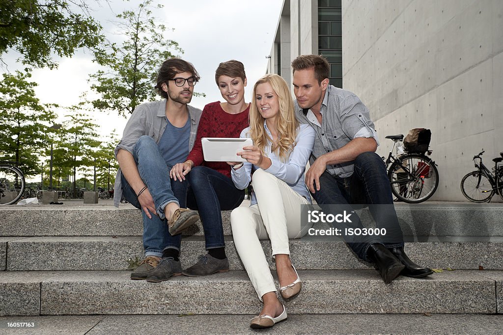 Quattro amici guardando un tablet - Foto stock royalty-free di Abbigliamento casual