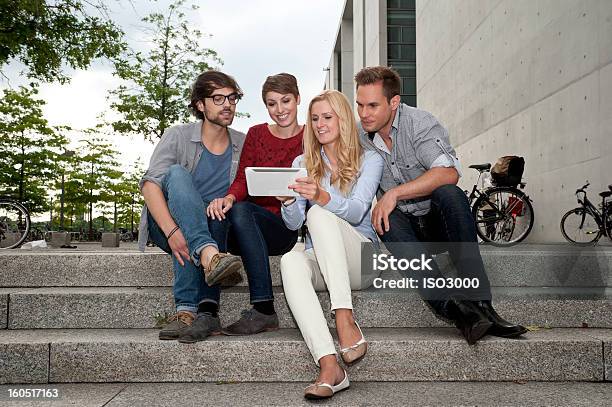 Quattro Amici Guardando Un Tablet - Fotografie stock e altre immagini di Abbigliamento casual - Abbigliamento casual, Ambientazione esterna, Amicizia