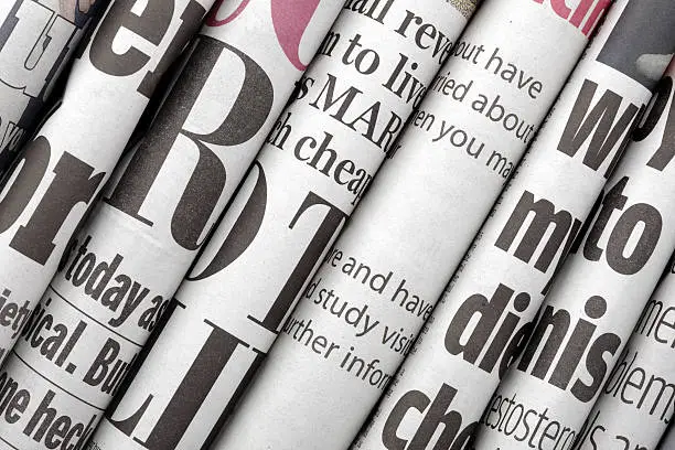 Newspaper headlines shown side on in a stack of daily newspapers