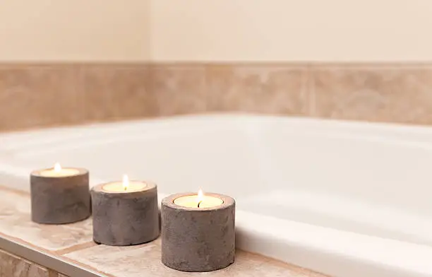 Three candles in concrete candle holders decorating bathroom.