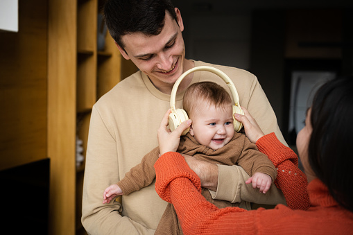 Mujer y hombre sosteniendo a su pequeña niña de cinco o seis meses. Familia feliz, paternidad, concepto de amor. Concepto de música para niños photo