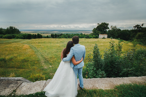 Wedding photographer with camera takes pictures of the beautiful bride and groom outdoors