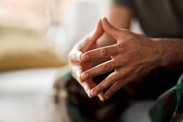 Hands clasped, soldier sitting and military person with anxiety, depression or problem on sofa. Army man, couch and ptsd, stress and crisis after war, trauma and waiting in living room alone in home