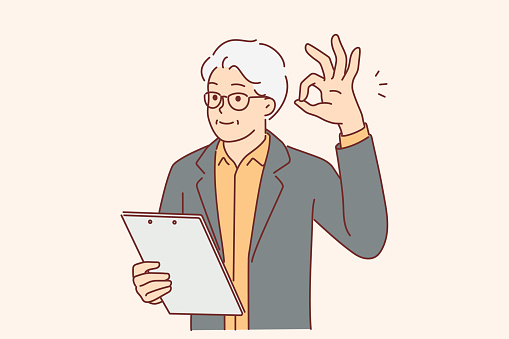 Elderly businessman showing OK gesture and holding clipboard checking work of subordinates or contractors. Gray-haired man making affirmative OK sign with fingers demonstrating approval of plan