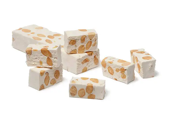 Pieces of Nougat with almonds and pistachio nuts on white background