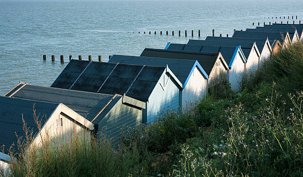 Beach Huts at Clacton-on-Sea, Essex, UK. Sun setting on the rear of a row of beach huts at Clacton-on-Sea, Essex, UK. clacton on sea stock pictures, royalty-free photos & images