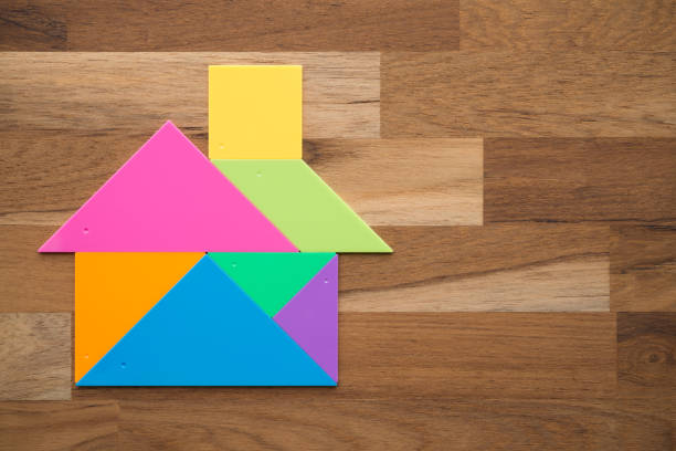 Colorful plastic tangram puzzle in home shape on wooden background. Concept of happy dream family, real estate property business, personal financial home loan, mortgage house concept.