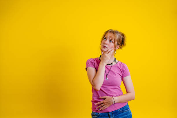 istock Pensive Young Woman Standing Against A Yellow Background 1605251324