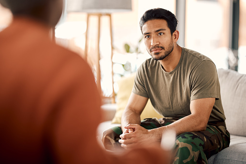 Listen, therapy and a military man with a psychologist for counselling, support and psychology. Young army, veteran or soldier person on therapist couch for mental health, consultation or help