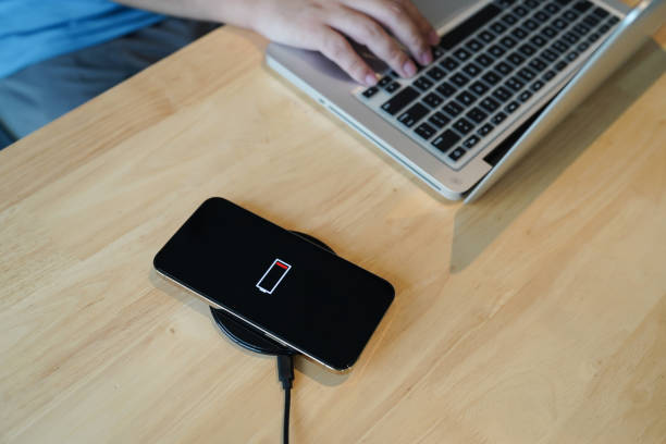 istock Charging mobile phone battery with wireless charging device in the table. Smartphone charging on a charging pad. Mobile phone near wireless charger Modern lifestyle technology concept 1605254609