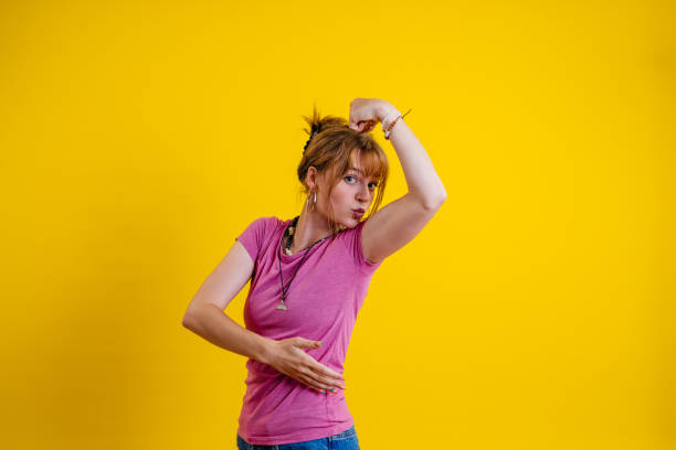 istock Young Woman Flexing Muscles Against A Yellow Background 1605277655
