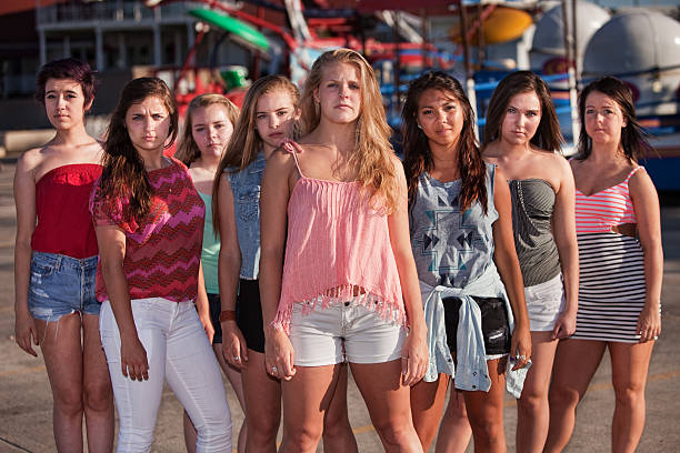 Group of eight serious teenage girls standing at an amusement park