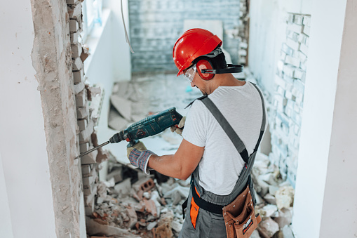 Track the crafting progress as a young male construction worker carefully forms an opening in the wall, marking a significant step in the renovation