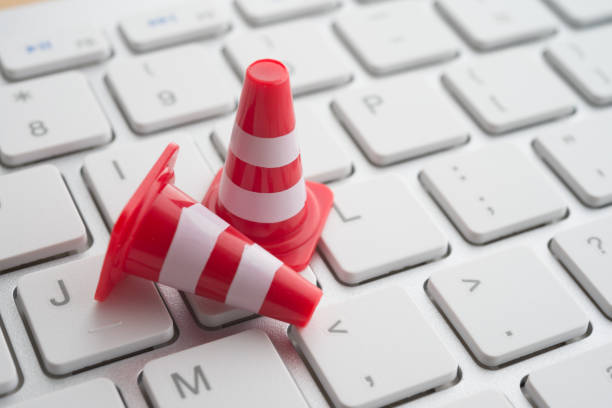 istock Close up orange white traffic warning cones or pylon on keyboard computer background with copy space. 1605303840