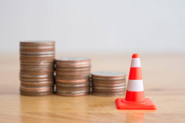 istock White orange under construction cone and  stacked coins as bar graph moving down. 1605305499