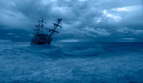 istock Sailing old ship in a storm sea in the background stormy clouds 1605316415