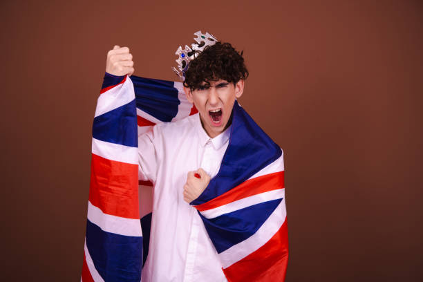 istock Young funny guy with british flag posing on brown background. 1605329988