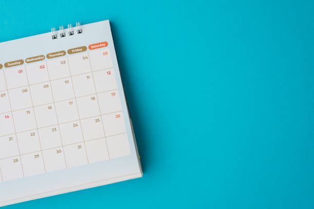 istock Flat lay of white empty clean monthly calendar on blue background. 1605331034