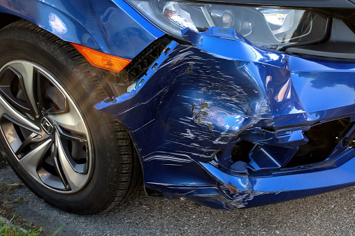 The front end of a blue automobile that received heavy damage in an accident.
