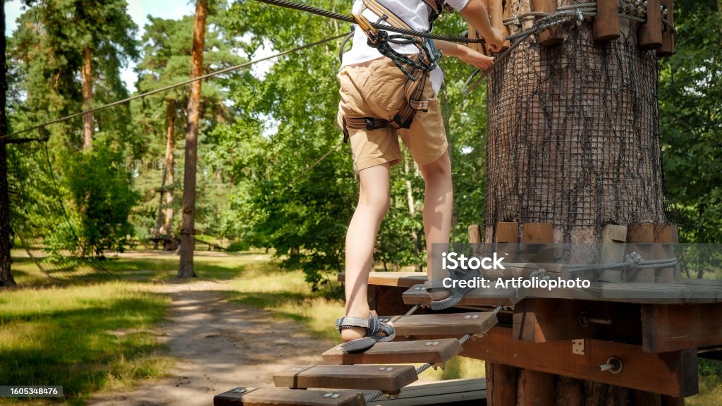 Child's feet walking over wooden rope bridge strung high between trees in forest - Royalty-free 13 - 19 Yaş arası Stok görsel Child's feet walking over wooden rope bridge strung high between trees in forest - Royalty-free 13 - 19 Yaş arası Stok görsel
