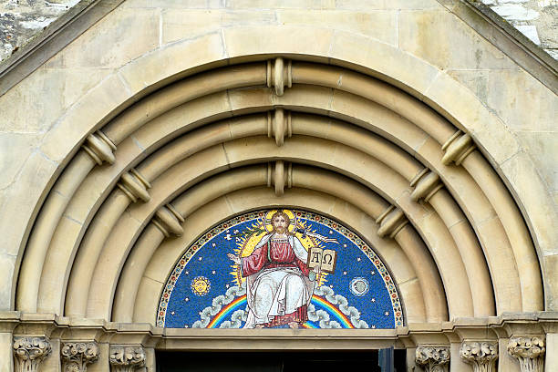 Alpha and omega Mosaic with Jesus Christ with open book containing Gods words Alpha and Omega. Jesus is sitting on a cloud and a rainbow. Mosaic is part of portal and entrance to parish church Gaukirche St. Ulrich in Paderborn, North Rhine Westfalia, Germany. Church was built in 12th, modified by royal architects Franz Christoph Nagel (1699-1764) with baroque elements. Church is located at opposite side to cathedral of Paderborn. In former medieval times parisch church was for folk and people under the aegis of priest of St. Ulrich. paderborn photos stock pictures, royalty-free photos & images
