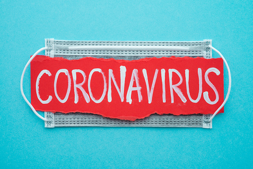 Text CORONAVIRUS with gray protect face mask on blue background with copy space. Global novel coronavirus (Covid-19) outbreak around the world concept. Corona virus was detected in Wuhan, China.