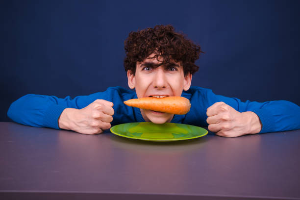 istock Funny silly guy eats carrots. Diet and healthy lifestyle. 1605361184