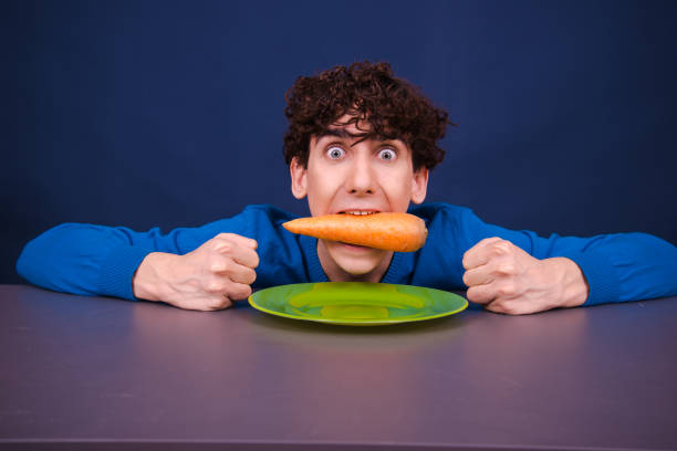 istock Funny silly guy eats carrots. Diet and healthy lifestyle. 1605370622