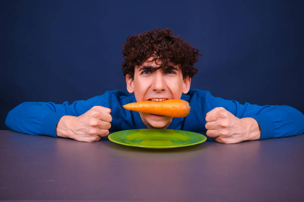 istock Funny silly guy eats carrots. Diet and healthy lifestyle. 1605371785