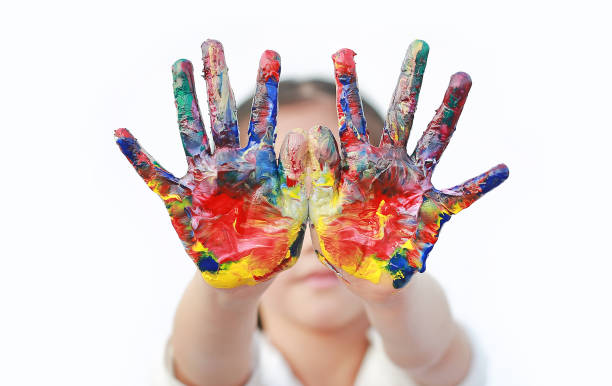 istock Close up kid hands painted in colorful paints isolated over white background. 1605375152
