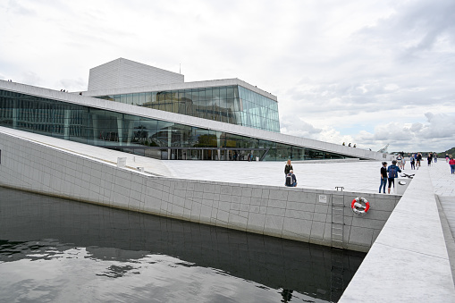 Oslo, Norway, July 5, 2023 - Locals and tourists walk across the marble roof of the Oslo Opera House (Norwegian: Operahuset).