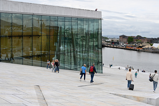 Oslo, Norway, July 5, 2023 - Locals and tourists walk across the marble roof of the Oslo Opera House (Norwegian: Operahuset).