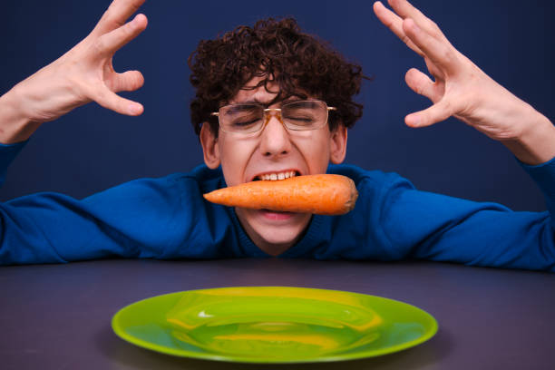 istock Funny silly guy eats carrots. Diet and healthy lifestyle. 1605383330